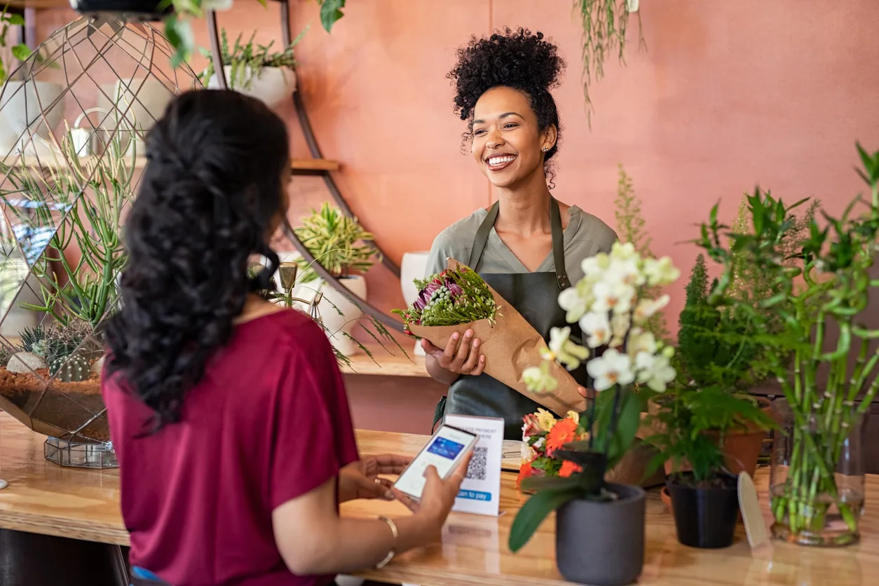 Happy friendly florist giving fresh bouquet to customer retail floral supplies