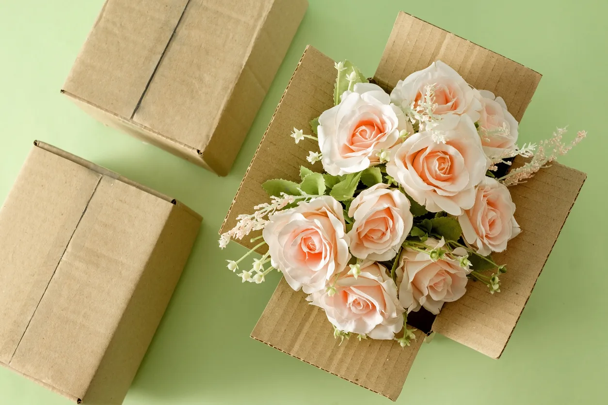 A beautiful blooming bouquet of pink roses in a parcel delivery cardboard box. Gift holiday concept and logistics service. retail floral supplies