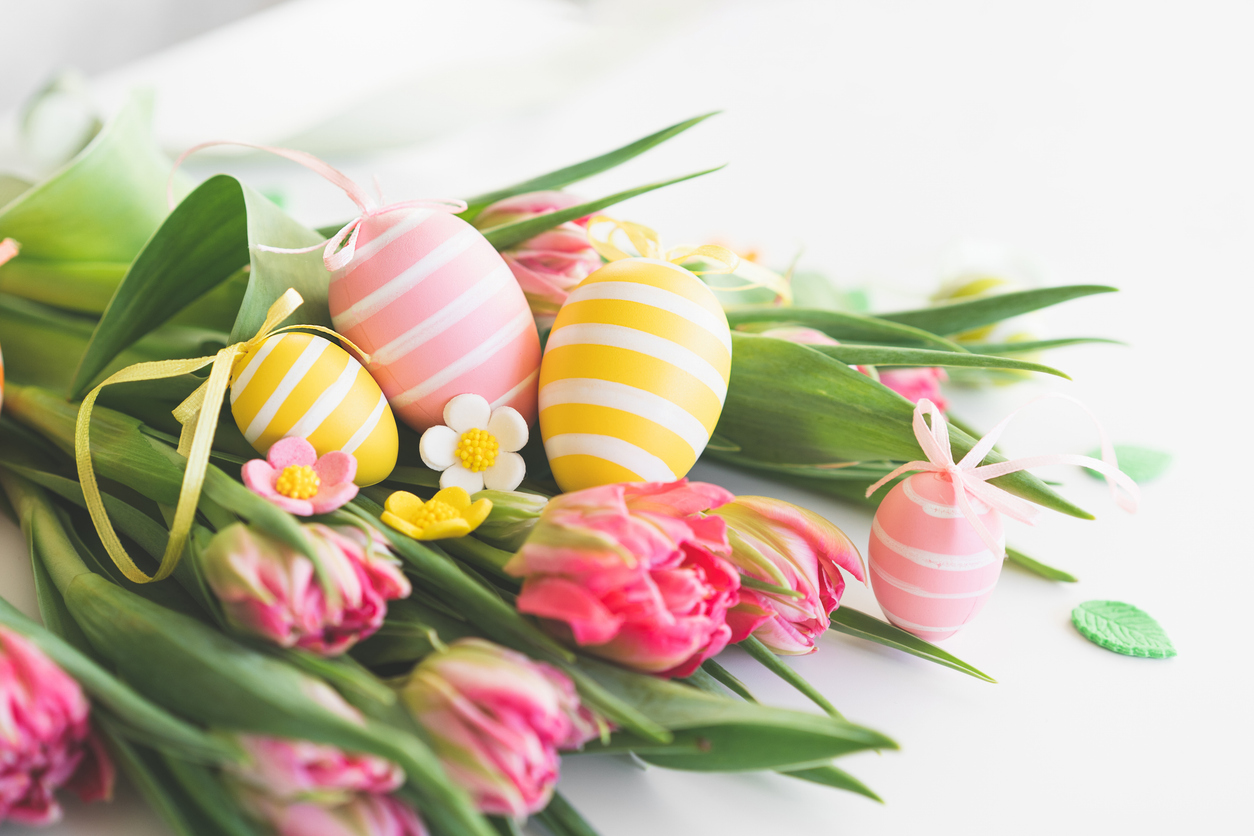 Stylish dyed easter eggs with spring flowers on white background. floral picks